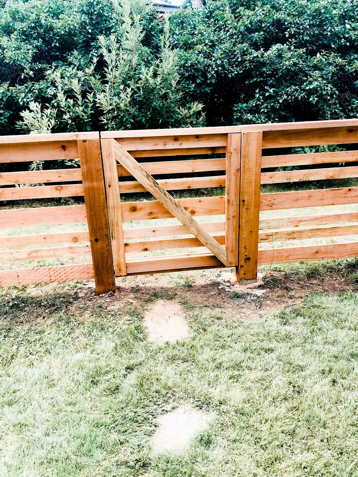 Wooden ranch-style gate with green hedges — fence installation in Loveland or Windsor, CO